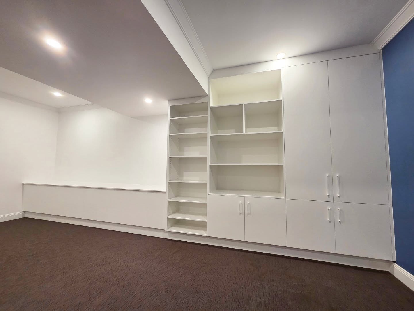 Custom bedroom wardrobes with built-in shelving and blue accent wall