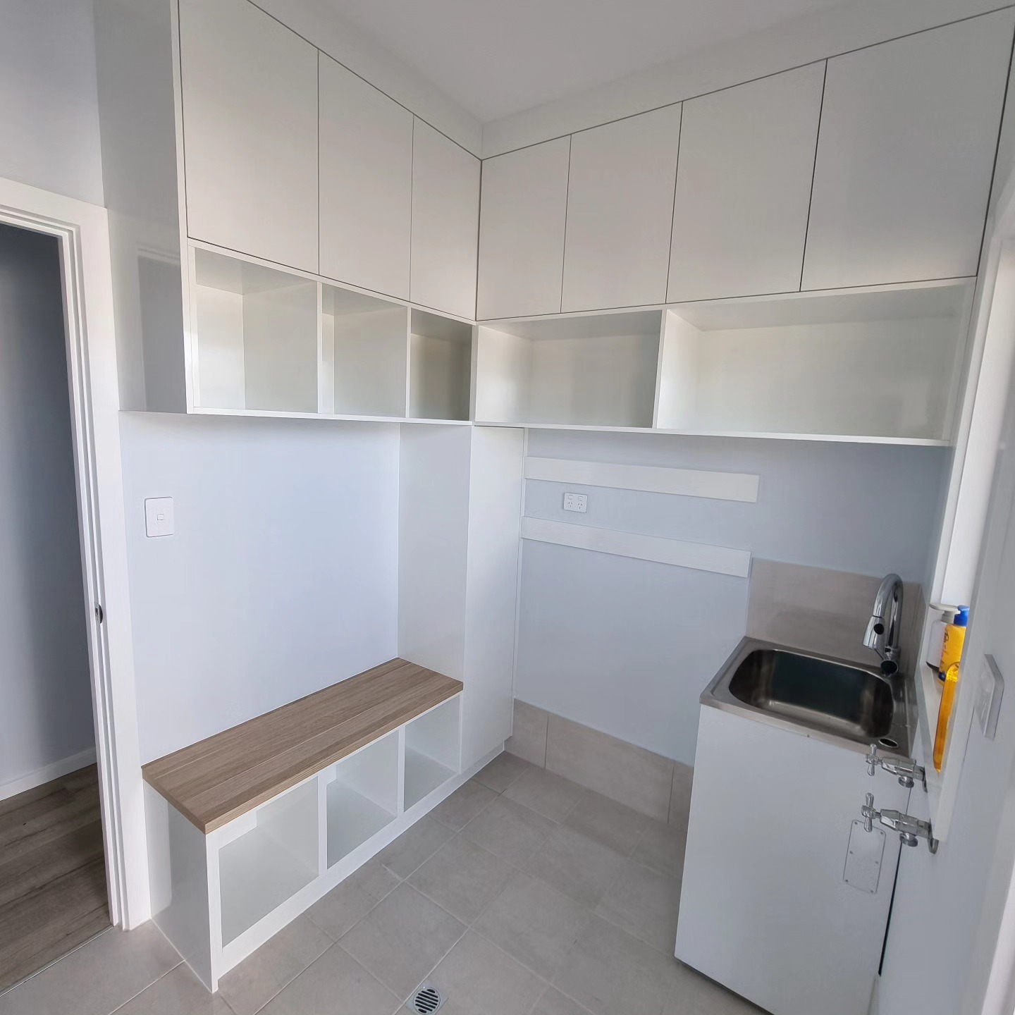 White custom storage cabinetry with open shelving for laundry room