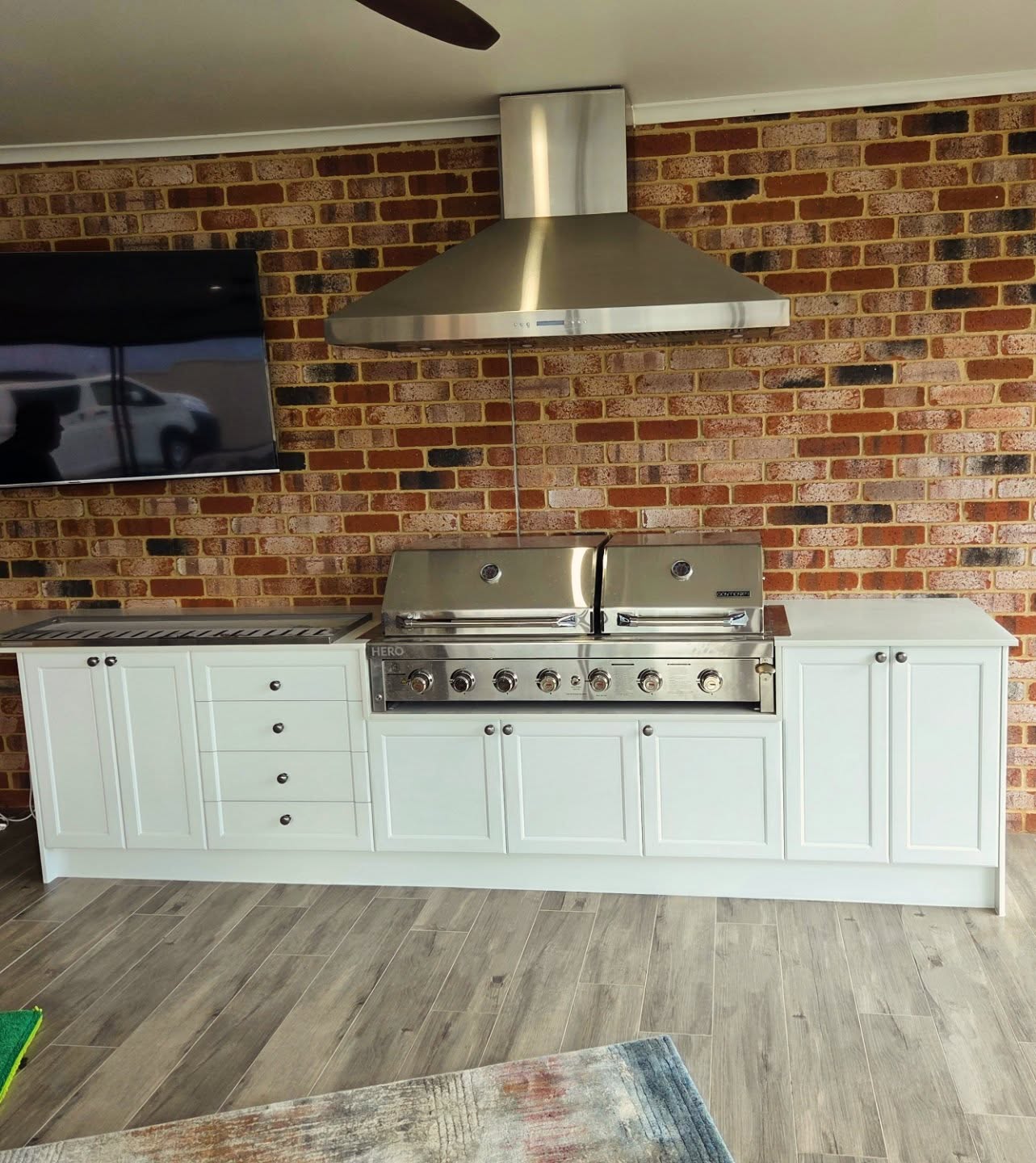 Outdoor BBQ kitchen with brick splashback and built-in grill